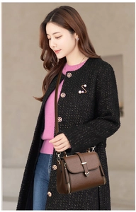 Détail d'un sac bandoulière en cuir grainé marron foncé avec boucle dorée sur un manteau