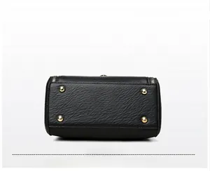 Détail du fond d'un sac en cuir noir avec quatre clous dorés et fermeture éclair latérale