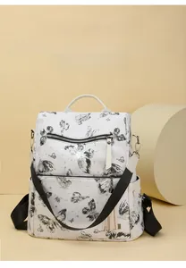 Detail of white butterfly print backpack featuring front zip pockets and tassel charm