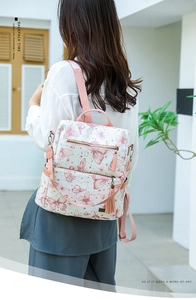 Close-up of white backpack with pink butterfly print and stylish fringe tassel detail