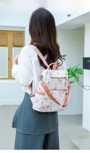 Close-up of white butterfly print backpack with pink tassel and adjustable straps on model