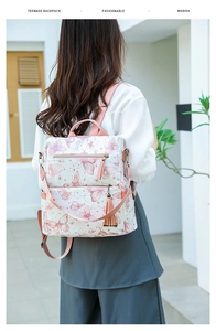Detailed back view of a white butterfly print backpack with pink tassel and dual zipper