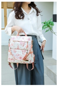 Detail of butterfly print backpack with pink tassel charm and adjustable straps