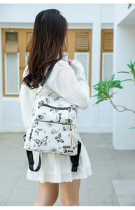 Close-up of a white butterfly print backpack featuring leather tassels and metal logo