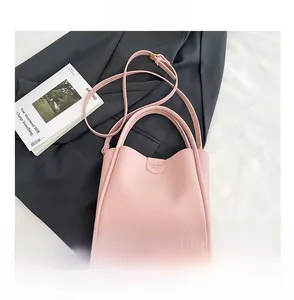 Détail du sac à main rose en cuir grainé avec texte embossé et bandoulière élégante