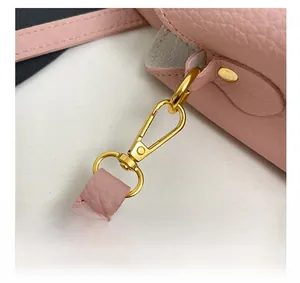Détail du sac seau en cuir rose avec crochet pivotant doré brillant et surpiqûres