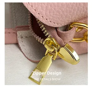 Gros plan sur la fermeture éclair dorée du sac seau en cuir grainé rose clair élégant