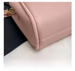 Gros plan sur un sac seau en cuir grainé rose avec coutures fines et détails dorés