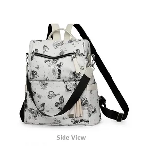 Side view detail of a white butterfly print backpack with fringe charm and silver hardware