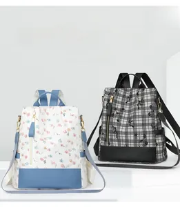 Detail of floral and plaid anti-theft backpacks on a minimalist white platform
