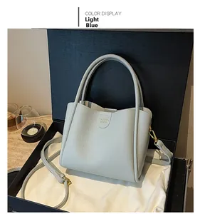 Sac seau en cuir bleu avec lettrage doré présenté dans un coffret cadeau de luxe