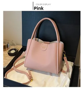 Vue détaillée du sac seau rose à texture litchi avec ferrures dorées et texte de mode
