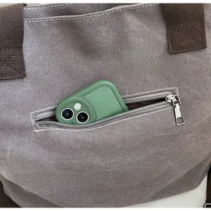 Detail of canvas tote bag featuring a practical metal zipper pocket for phone storage