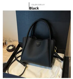 Détail du sac seau noir grainé avec lettrage doré dans une boîte cadeau de luxe