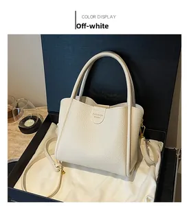 Détail d'un sac seau en cuir beige dans un coffret cadeau avec garniture dorée