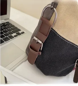 Close-up of canvas tote side with tricolor stitching and brown leather strap detail