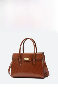 Detail of vintage brown oil-wax leather handbag with golden metal twist lock and large capacity