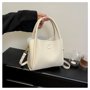 Détail du sac seau en cuir grainé beige avec boucles dorées et logo élégant