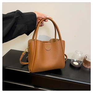 Vue détaillée du sac seau en cuir grainé marron avec finitions dorées et logo de marque