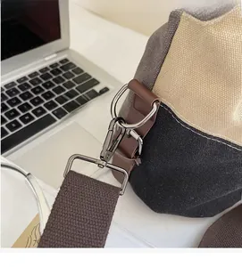 Detail of durable gunmetal hook and brown leather strap connector on canvas tote bag