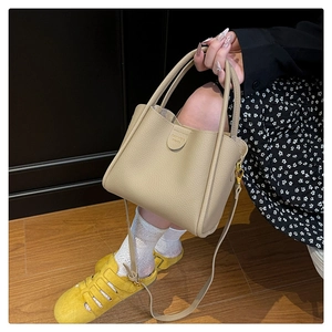 Détail du sac seau beige à motif litchi avec logo FASHION BAGS et finitions dorées