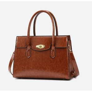 Detail of dark brown vintage faux leather handbag with golden oval twist lock clasp