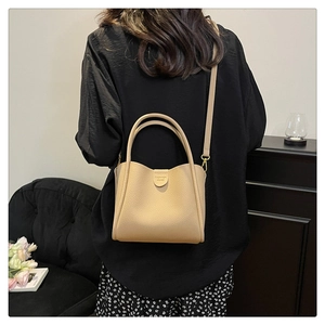 Vue détaillée du sac seau beige avec texture litchi et bandoulière amovible réglable