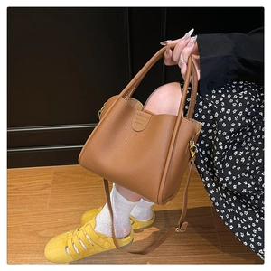Détail du sac seau en cuir grainé marron avec lettrage doré et texture cuir véritable