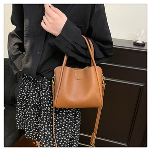 Détail du sac seau en cuir grainé marron avec finitions dorées et logo de la marque