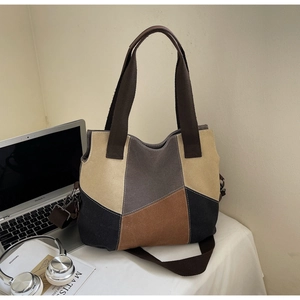Detail of color-block canvas tote bag on desk with laptop and artistic props