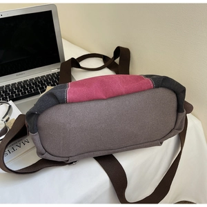 Detail of color-block canvas tote bag with brown strap on a white desk setting