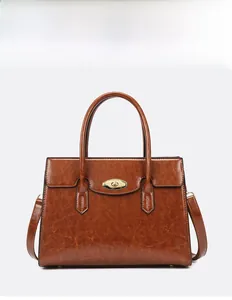 Detail of vintage caramel brown tote bag featuring golden oval twist lock and oily leather texture