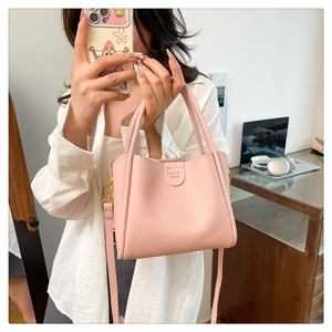 Détail d'un sac seau en cuir rose grainé avec des finitions dorées et un logo chic