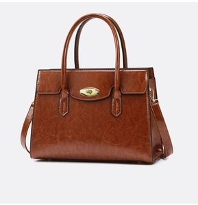 Detail of vintage oil wax leather handbag featuring a golden oval metal twist-lock buckle