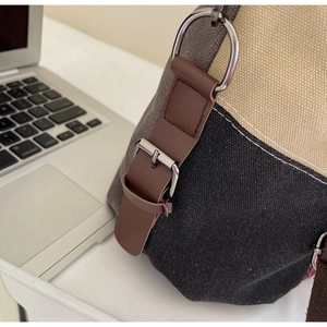 Detail of canvas tote bag showing tri-color stitching and adjustable leather strap with buckle