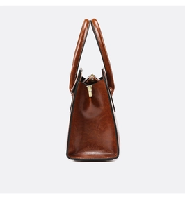 Detail of vintage brown leather tote bag with glossy texture and gold zipper closure