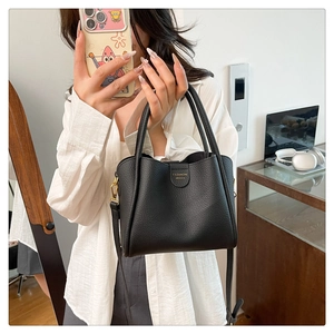 Détail du sac seau noir en cuir grainé avec finitions dorées et logo élégant
