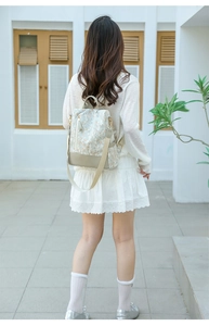 Rear view of a floral canvas backpack worn by a model against a modern white wall