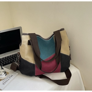 Detail of color-block canvas tote bag with multi-color stitching and brown shoulder strap