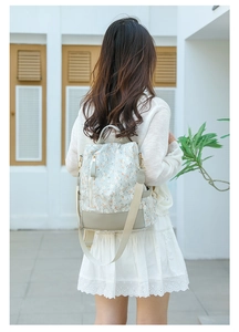 Detailed view of floral lace pattern and leather patchwork on light blue backpack