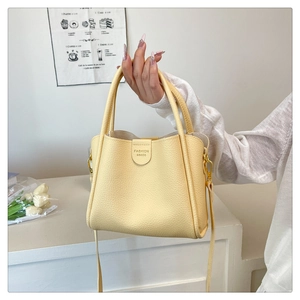 Gros plan sur le cuir grainé jaune crème et les crochets dorés du sac à main seau