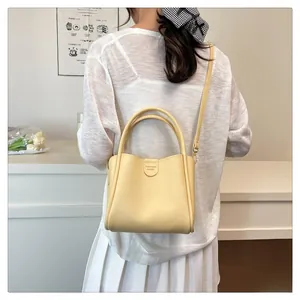 Détail du sac seau en cuir jaune grainé avec bandoulière réglable et logo de mode élégant