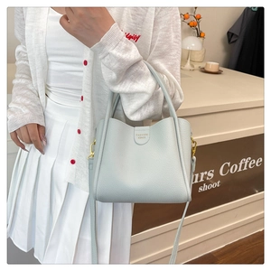 Détail du sac seau bleu clair motif litchi avec ferrures dorées et logo mode