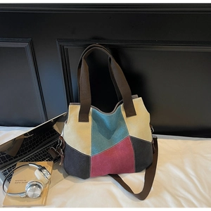 Detail of color-block canvas tote bag with brown straps, laptop and headphones setup