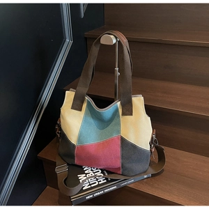 Detail of color-block canvas tote bag with brown straps on dark wooden stairs