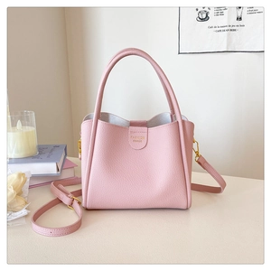 Détail du sac seau rose avec cuir à texture litchi et finitions dorées élégantes