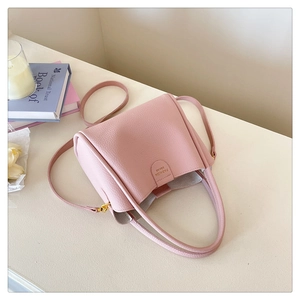 Détail du sac seau en cuir litchi rose clair avec fermoir doré et deux bandoulières