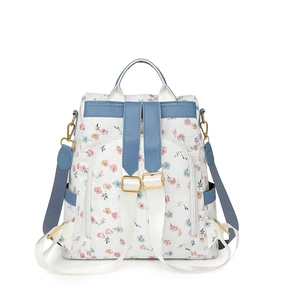 Detailed close-up of floral backpack showing blue leather trim and golden metal buckles