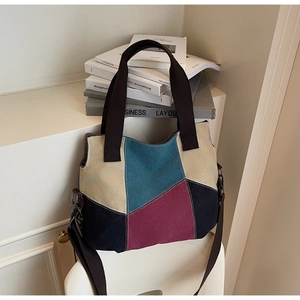 Detail of color-block canvas tote showing geometric segments and brown shoulder straps