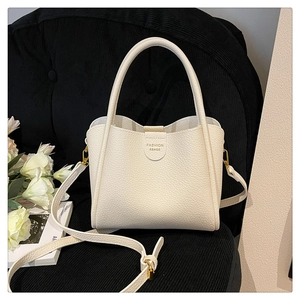 Détail du sac cabas en cuir grainé blanc avec inscription sur un fauteuil noir chic
